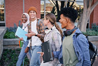 Four students walk to class on a college campus outside