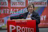 AFT president Randi Weingarten speaks in May 2024 in front of a  sign that says Raises Justice Community