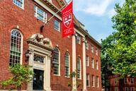 A flag with the Harvard University logo hangs above the entrance of Harvard's Lehman Hall. 