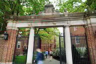 People enter Harvard Yard through a gate.