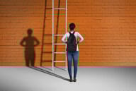 A student stands in front of a ladder with a couple of missing rungs.