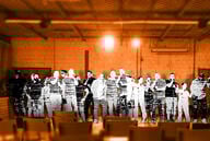 A group of people on crowded stage without an audience.