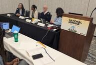 Four panelists sit at a table next to a lectern with the Education Writers Association logo on it.