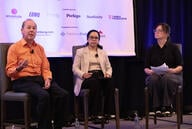 Three people are sitting in chairs on a stage participating in a panel discussion