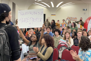 Students gather to protest anti-trans speaker Ian Haworth in the University of Albany's Campus Center; one holds a sign reading "transphobes, 0, trans people, 1."