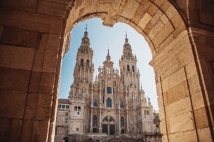 The ornate facade of the Santiago de Compostela Cathedral, as seen through an archway.