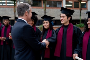 Academic shaking hands with graduates.