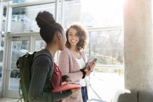 Two female students walk together in a hallway.