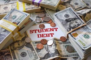 A pile of U.S. currency—bundles of $100 bills, scattered $20 bills and some coins—with the words "student debt" in the middle of the pile.