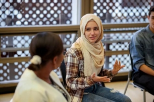 A student wearing a hijab talks to peers.
