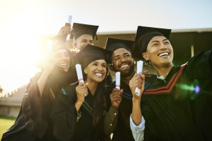 Five college students smile in academic regalia, holding their paper diplomas.