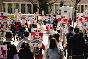 Striking Rutgers union members hold red and white signs