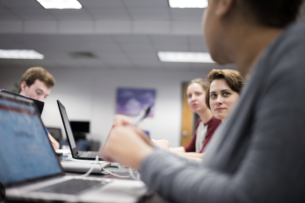 Several Tallahassee Community College students sit at a long table with laptops.