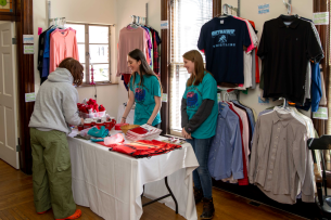 Two student employees assist a student in selecting clothing items from the free clothing store on Wittenberg University's campus.