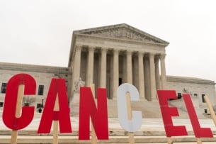 Letter signs spelling out "cancel" are held in front of the Supreme Court building