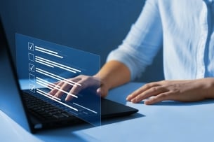 Cropped concept photo of hands on a laptop, filling out some kind of questionnaire. Color scheme is blue.