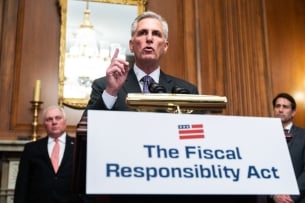 A sign that says The Fiscal Responsibility Act rests on a podium as Speaker Kevin McCarthy speaks behind it.