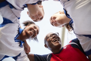 Three soccer players huddle with their coach