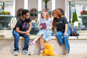 Three Brenau students sit in front of a fountain on campus.