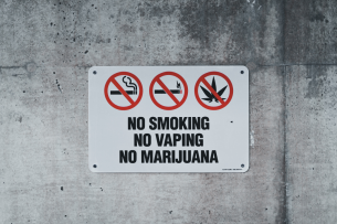 A sign on a concrete wall that reads NO SMOKING NO VAPING NO MARIJUANA