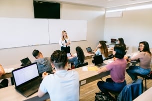 Teacher warmly engaging with diverse university students in a classroom