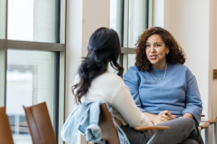 Two women seated talking, the older one giving advice to the other