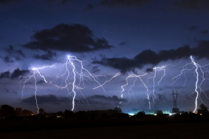 A photo of a thunderstorm—multiple storm clouds and lightning bolts can be seen against a dark blue/black background.