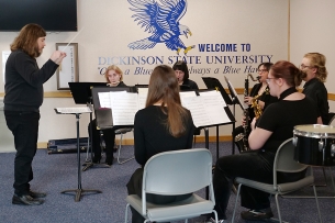 Dickinson State University musicians performing on their instruments, with "Welcome to Dickinson State University" and a hawk painted on the wall.