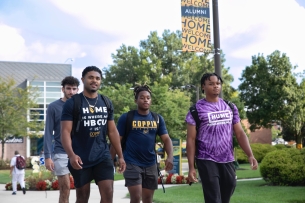 Four students, some in Coppin State University T-shirts, walk on campus.