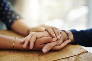 Close-up shot of two unrecognizable people holding hands in comfort