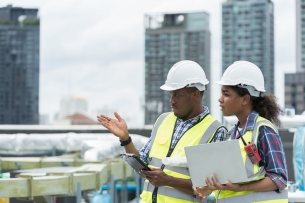 Two engineers work in a sewer pipe area at a construction site.