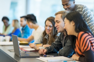 A group of college students works together on a laptop