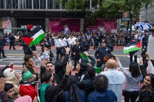 Palestinian supporters waving flags face off across a New York City street from a group of Israeli supporters waving flags