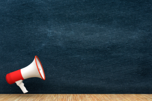 A red and white megaphone with a blank blackboard in the background.