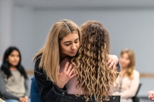 Two students hug and comfort each other during a support group session.