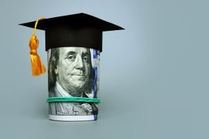 Roll of $100 bills with Ben Franklin peering out with a graduation mortarboard on his head