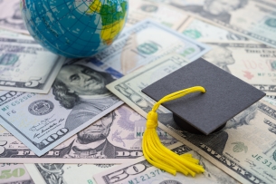 Mortar board sits on array of money bills alongside a globe