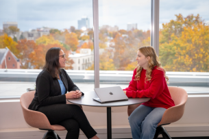 Rachael Heard sits at a table, meeting with a student