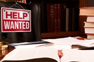Photo illustration of an empty desk and Help Wanted sign