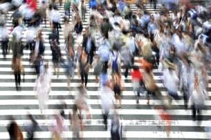 Blurred image of pedestrians on a crosswalk with black and white horizontal stripes