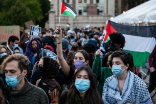 Students, clad in masks, hold up Palestinian flags during a protest on Columbia's campus.