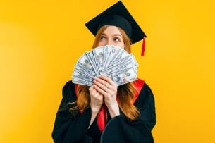 Woman in a cap and gown holding a fan of dollar bills
