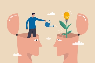 Two faces with the tops of their heads open face each other; in one open head, a man stands and pours from a watering can into the other, out of which grows a plant with a lightbulb on top