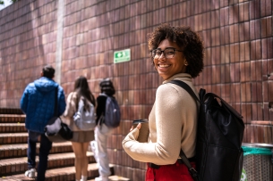 A young woman in college walks up the stairs behind her peers