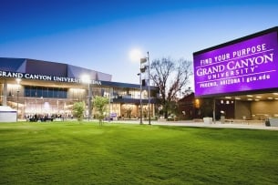 The campus of Grand Canyon University showing the front of an arena and a large electronic sign