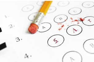 A No. 2 pencil with a well-worn eraser lies atop a standardized test form with multiple choice bubbles. The three bubbles in the foreground of the picture read “SAT.”
