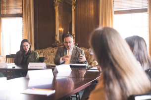 Secretary of Education Miguel Cardona and Dartmouth president Sian Leah Beilock sit at a large table, with two students in the foreground.