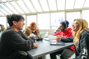 LaGuardia Community College students sit at a table, talking.