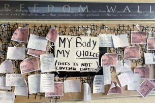 Posters that read "my body, my choice" cover a display of small black crosses on the Freedom Wall at Pepperdine University.