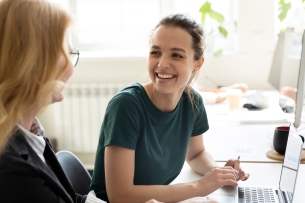 Happy smiling female trainee discussing business ideas with adult trainer 